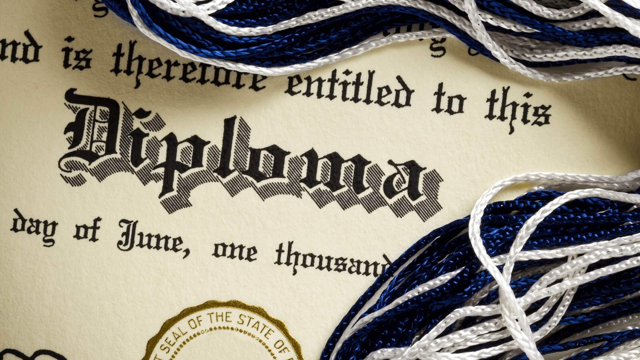 blue and white tassel ribbon next to real high school diploma with shiny gold raised state seal