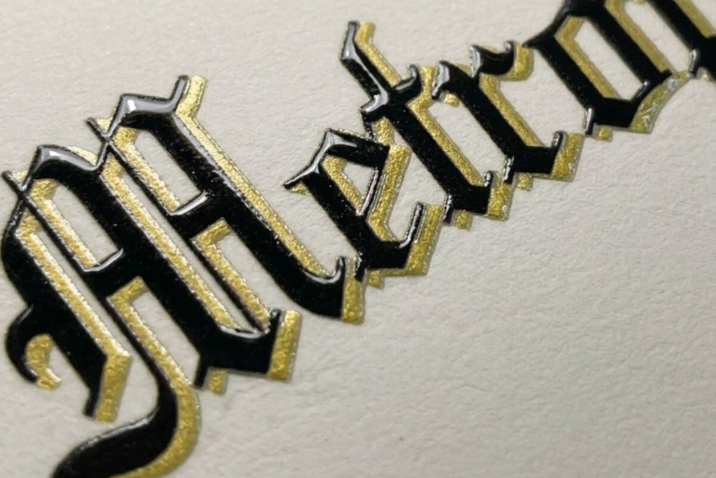 Close-up of raised black and gold outlined lettering on replica college diploma showing multi-color UV layered printing depth